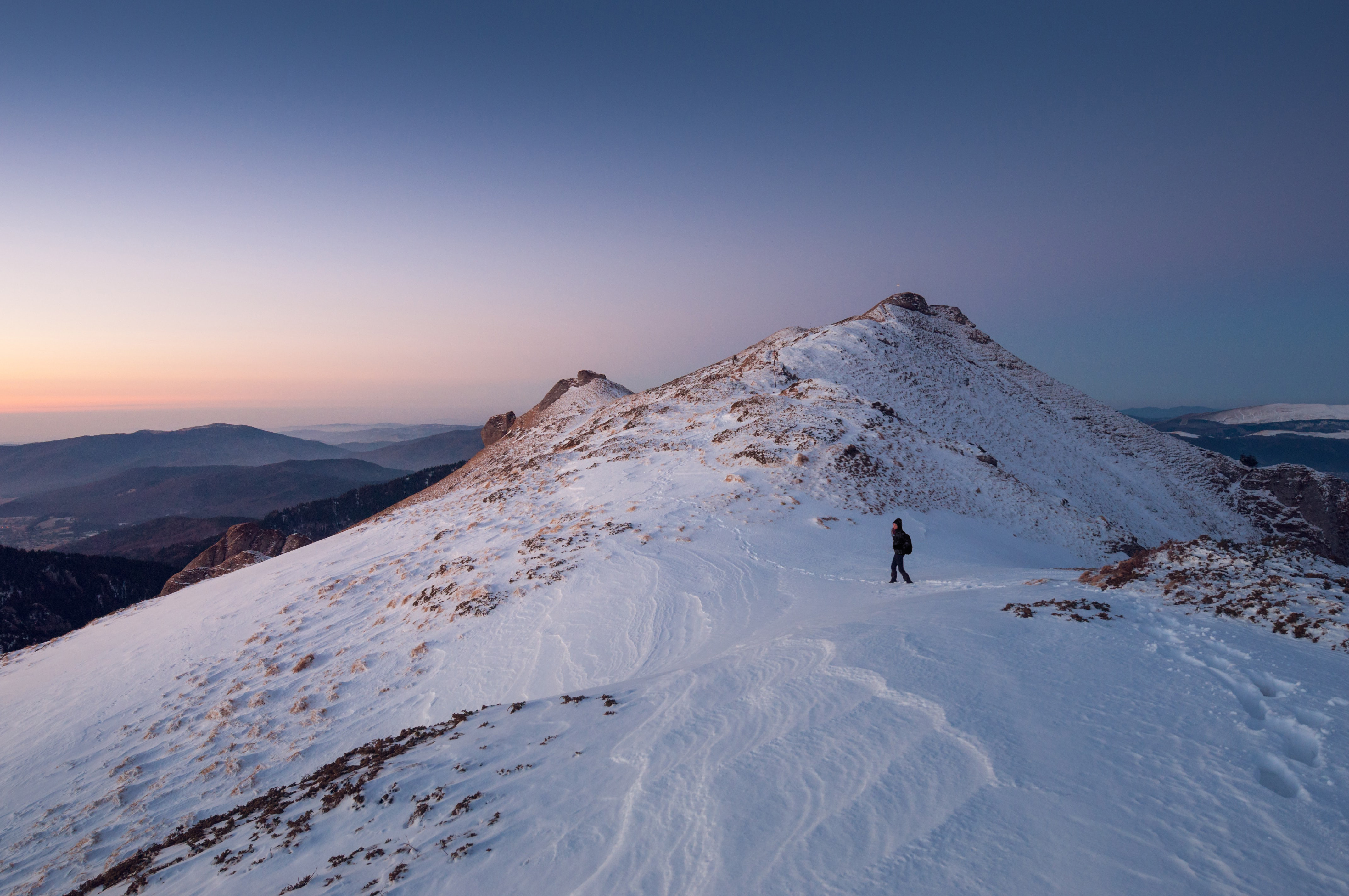 A woman is hiking on a snowy mountain at dawn